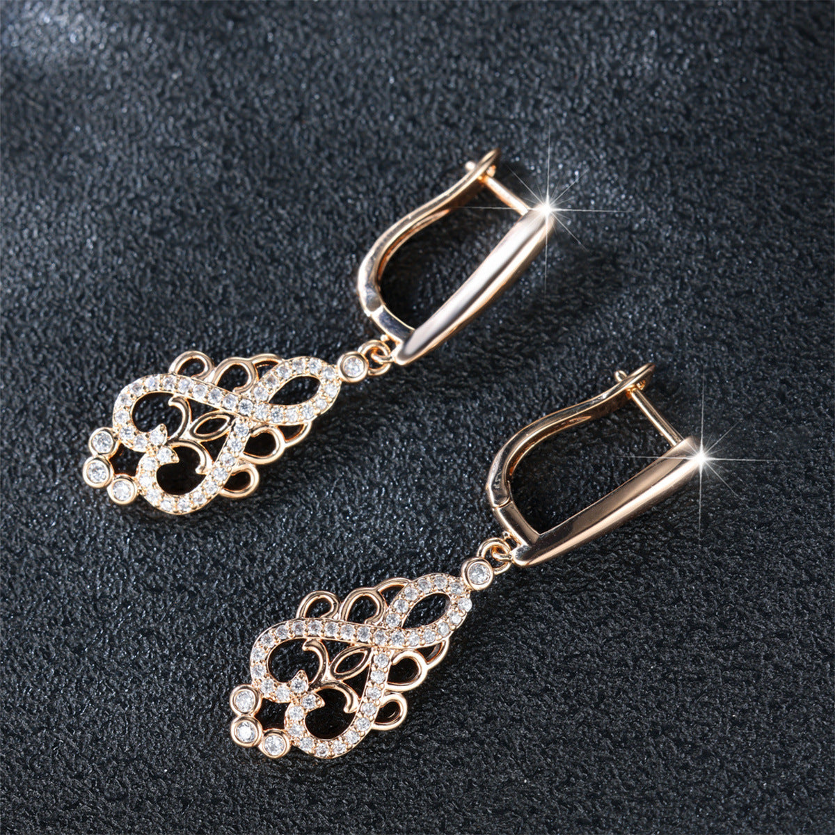 Pair of gold earrings with intricate designs on a dark background
