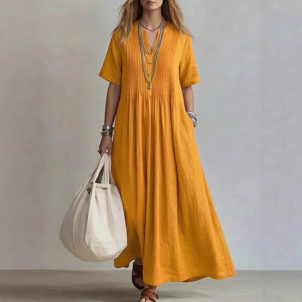 Woman wearing a mustard yellow dress holding a white bag against a neutral background