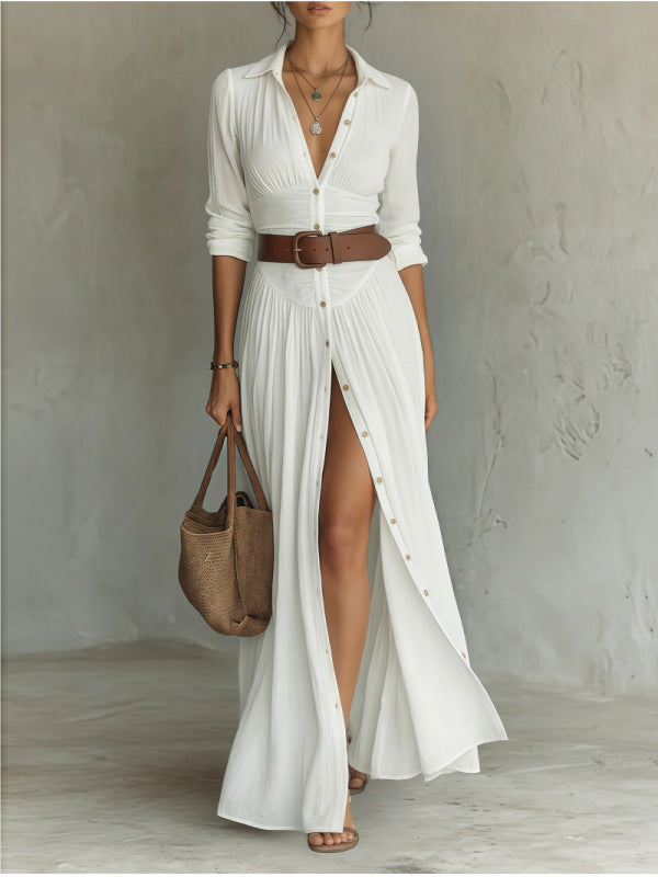 Woman wearing a white dress with a brown belt and holding a woven bag against a plain background