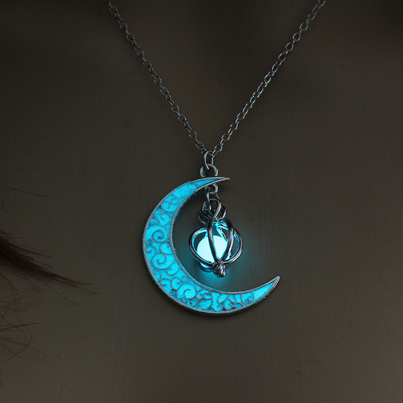 Glowing blue moon and star pendant on a chain against a dark background