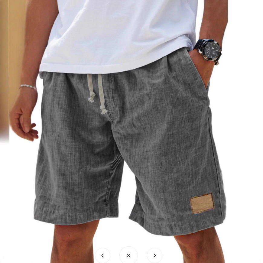 Person wearing gray shorts with a white shirt and watch on a blurred background