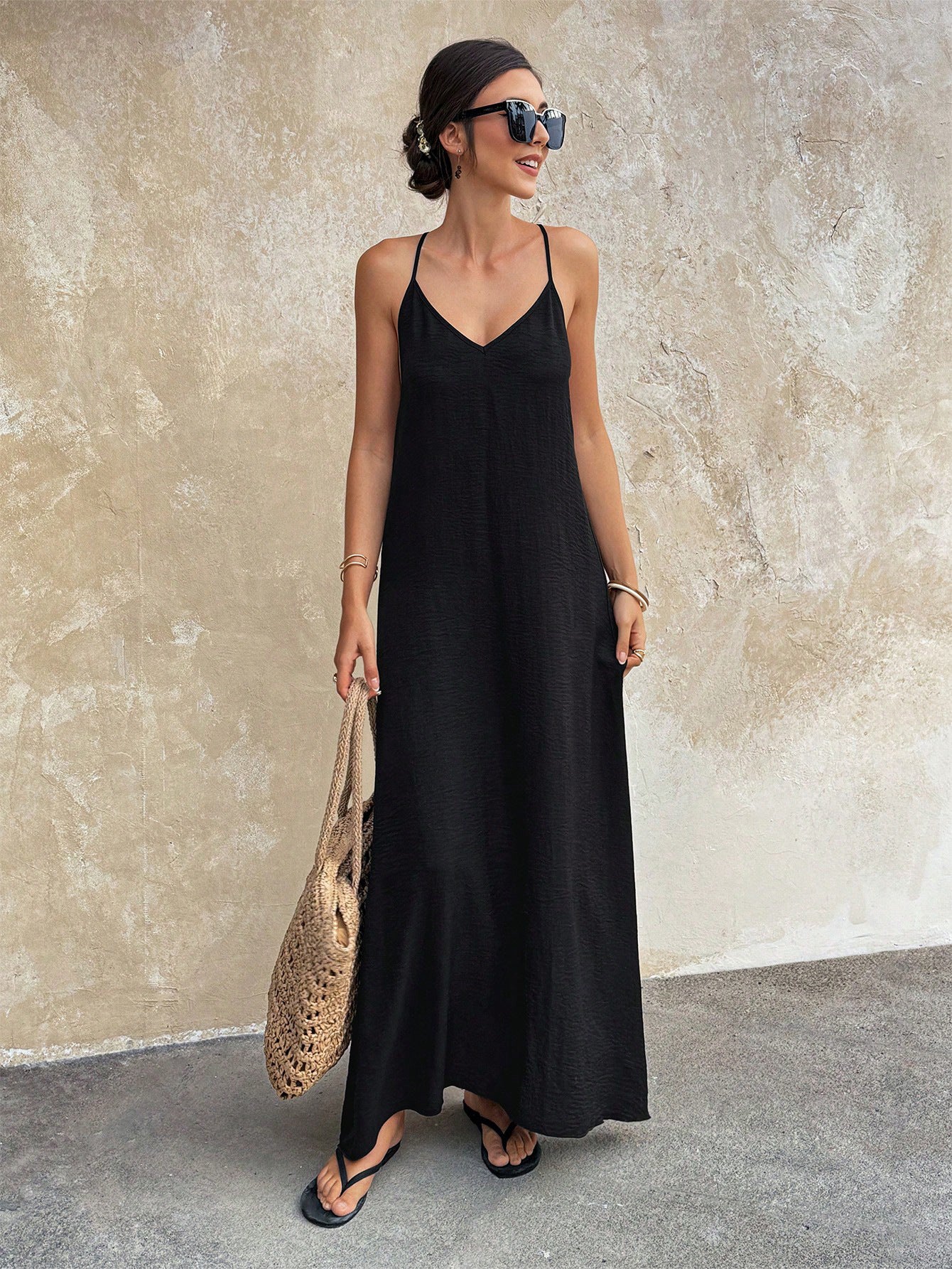 Woman wearing a black dress against a textured wall.