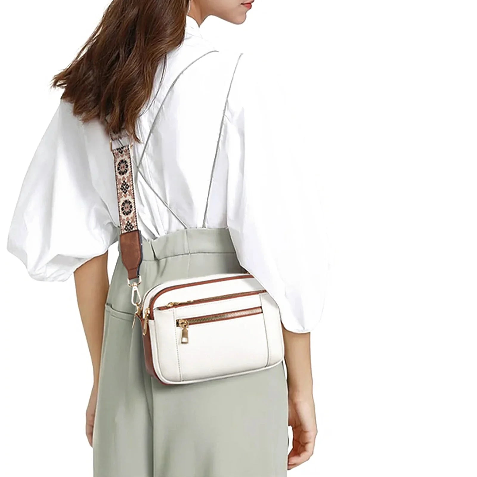 Woman wearing a white blouse and light green pants with a white crossbody bag.