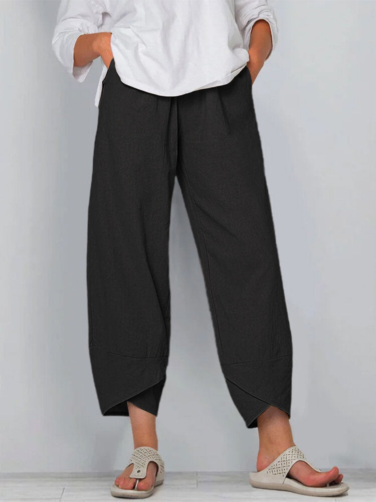 Person wearing black wide-leg pants and a white shirt on a plain background