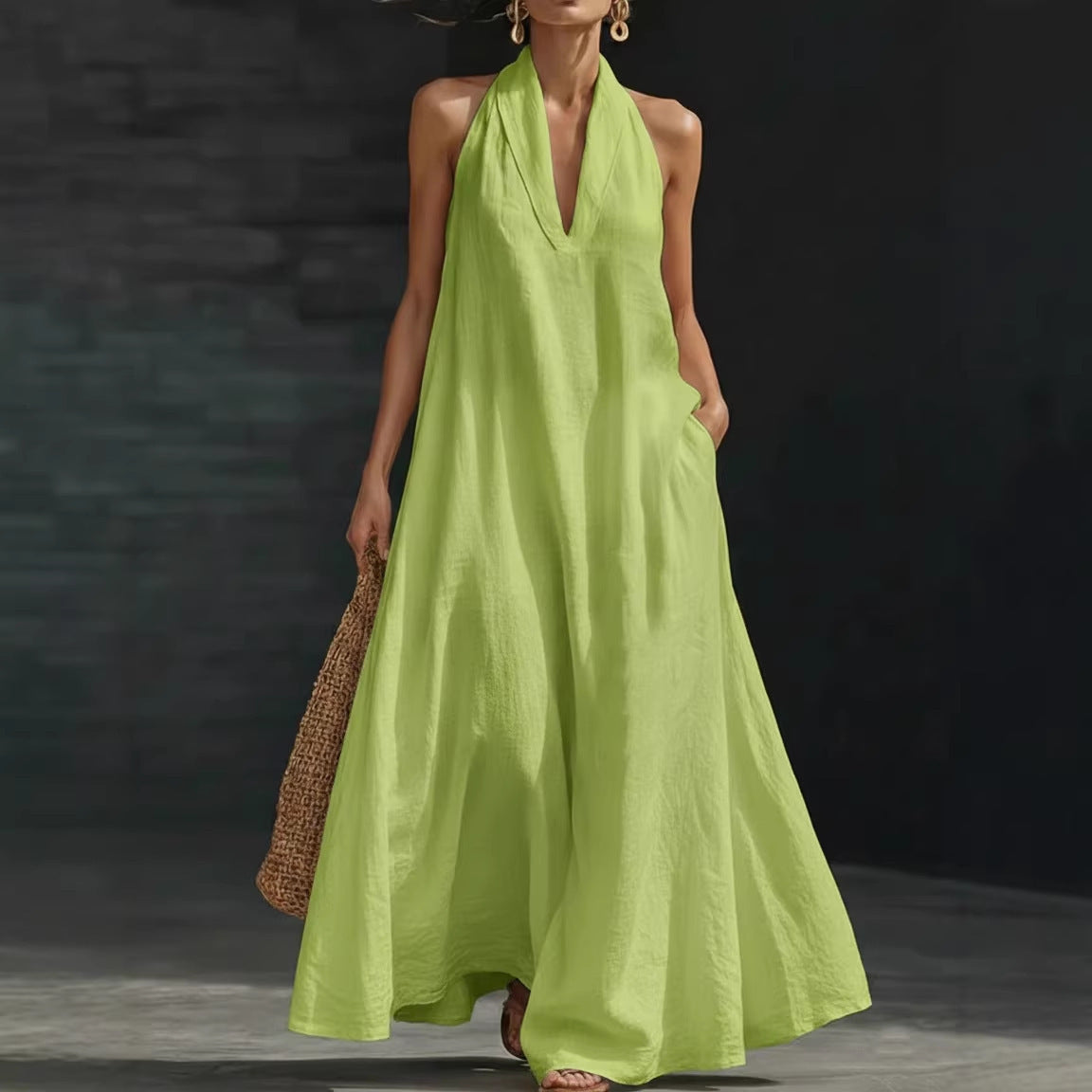 Woman wearing a bright green dress holding a woven bag against a dark background