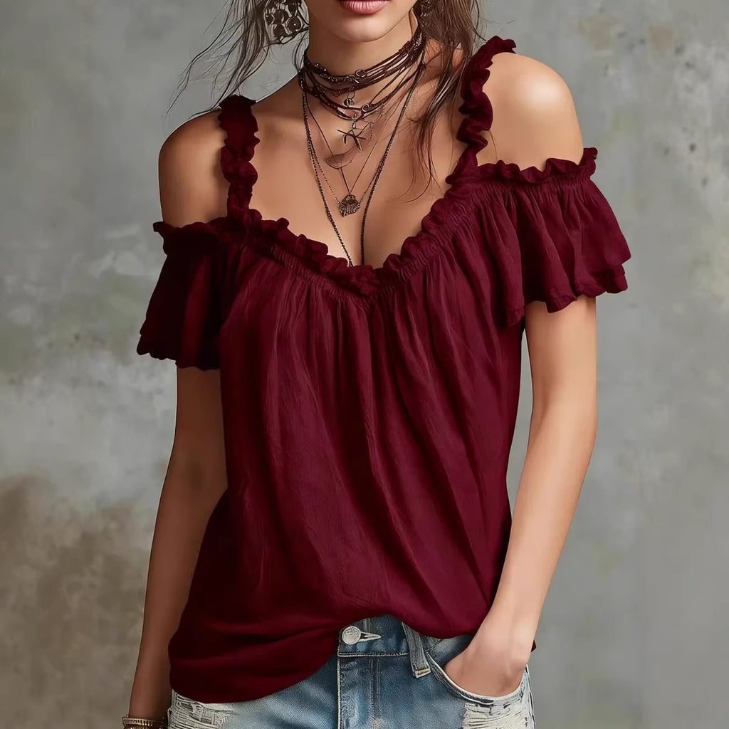 Woman wearing a burgundy off-shoulder top with denim shorts against a neutral background