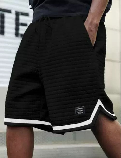 Black shorts with white trim worn by a person, blurred background