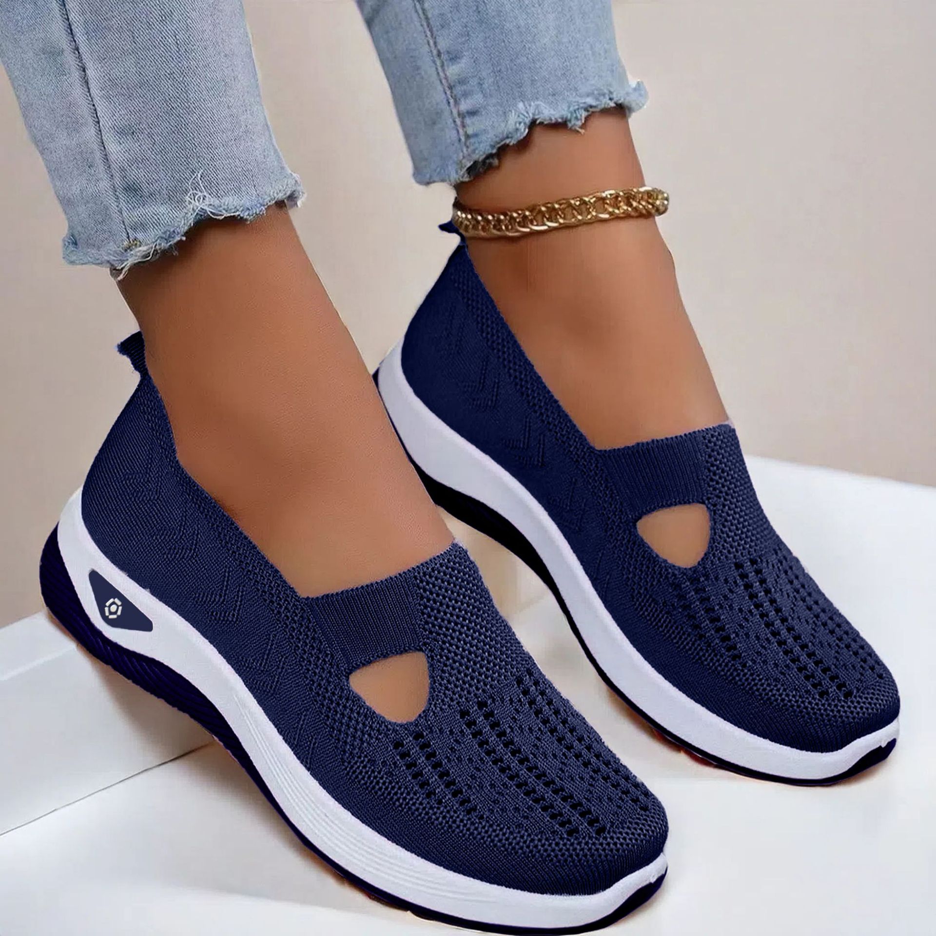 Navy blue slip-on shoes with white soles worn by a person on a light background