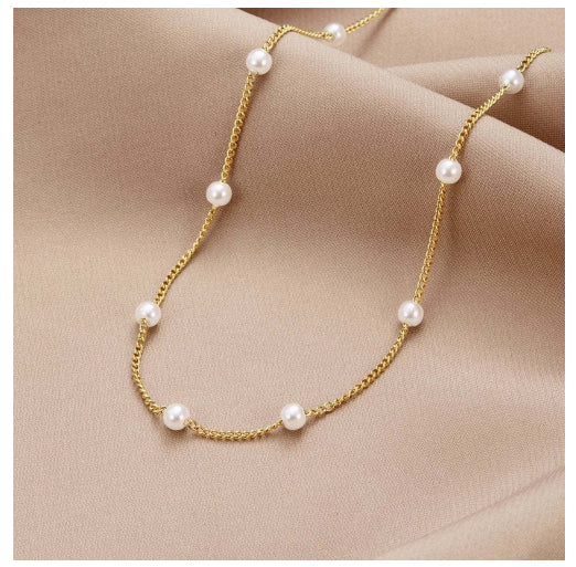 Gold chain necklace with pearls on a beige fabric background