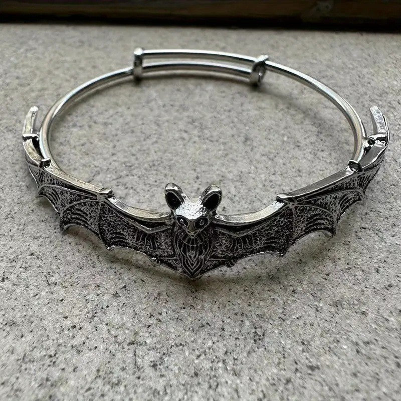 Silver bat-shaped bracelet on a gray surface