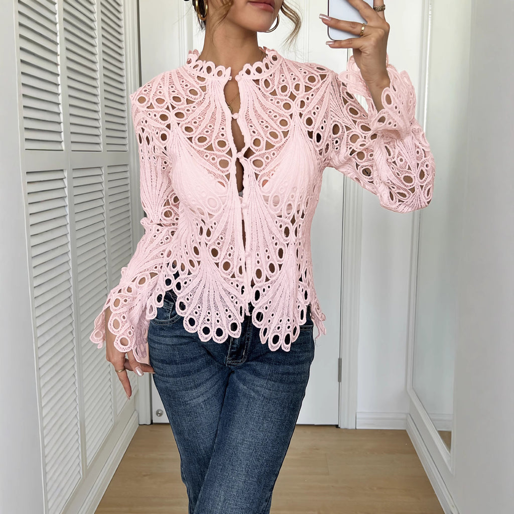 Person wearing a pink lace top and blue jeans in a room with white walls and wooden floor.