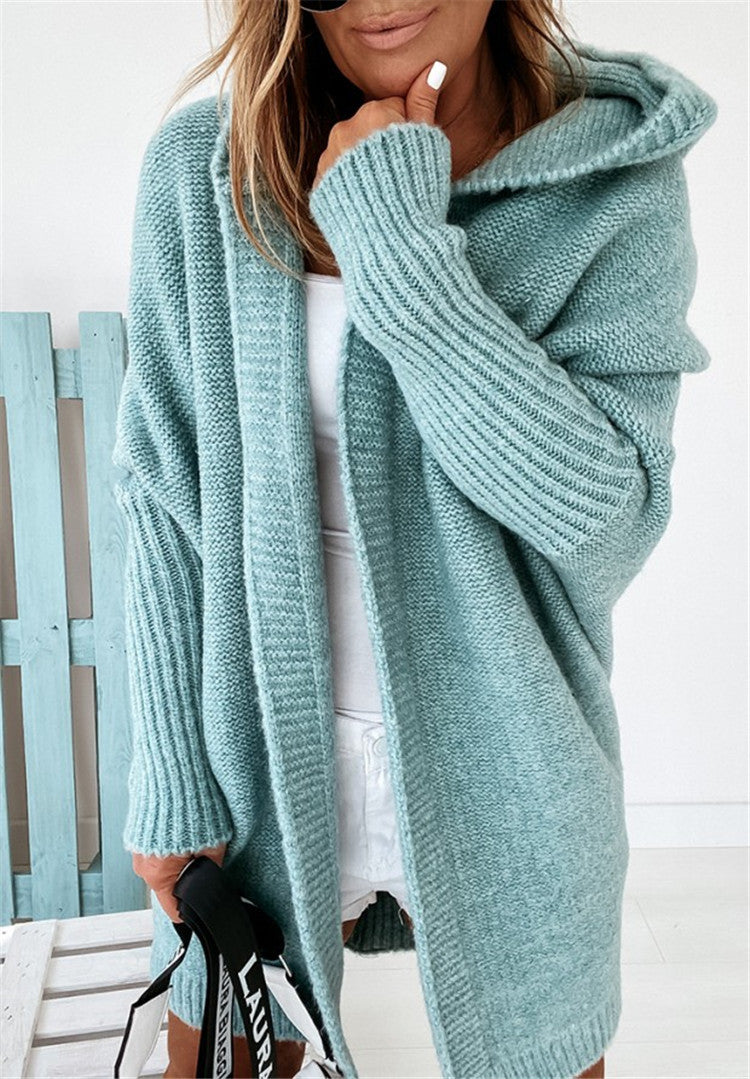Person wearing a light blue knitted cardigan with a white background