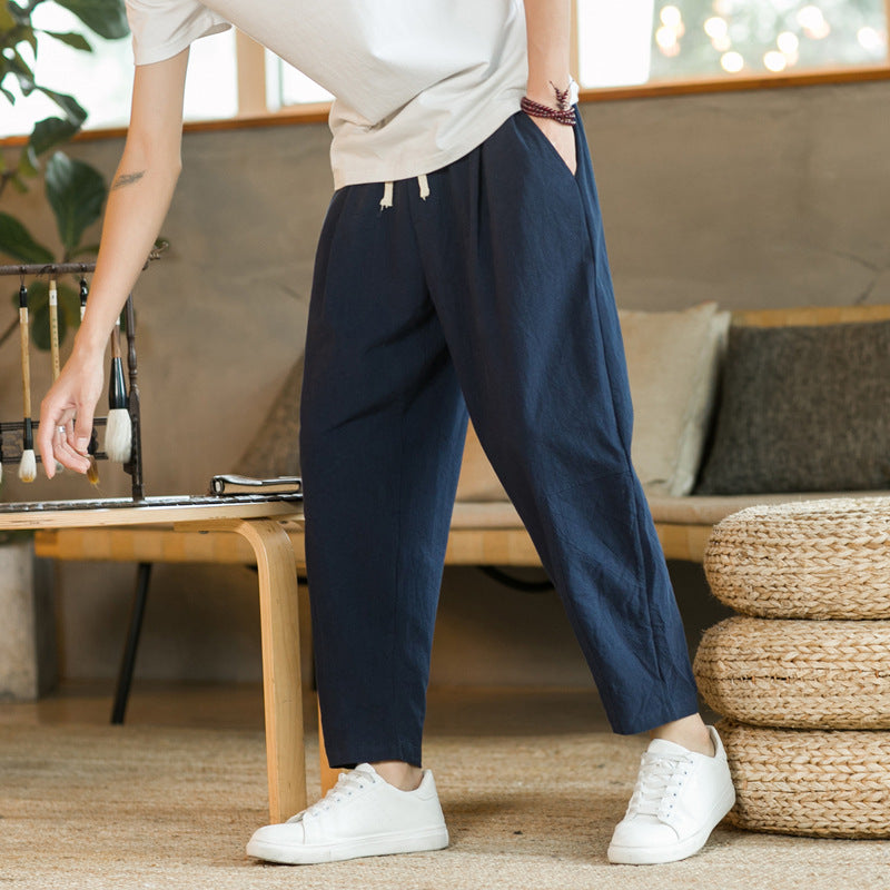Person wearing navy blue pants and white sneakers in a living room setting.