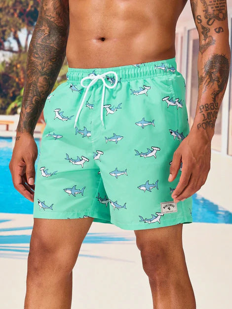 Person wearing teal swim shorts with shark pattern by a pool