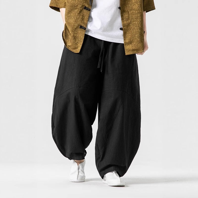 Person wearing black baggy pants with a white background