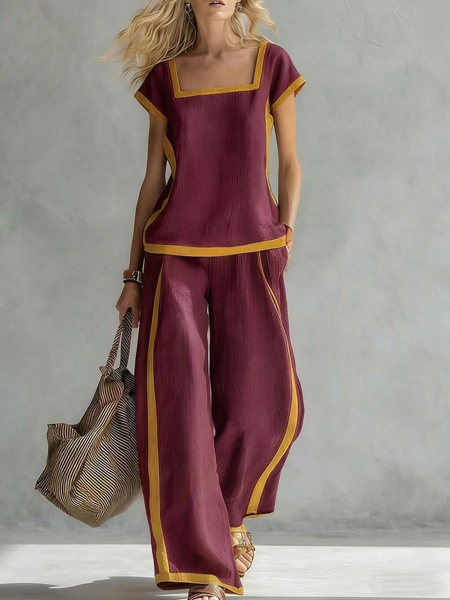 Woman wearing a maroon outfit with gold trim holding a bag against a gray background