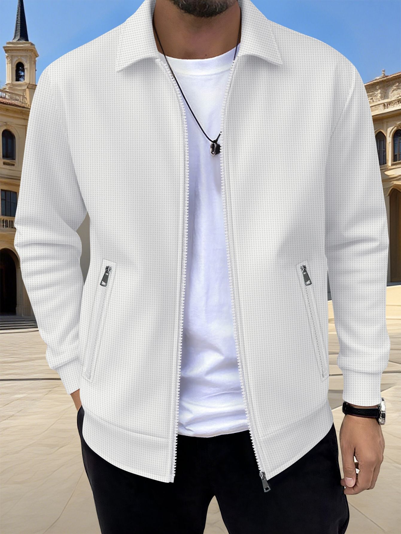Man wearing a white ribbed bomber jacket over a white shirt with a blurred architectural background
