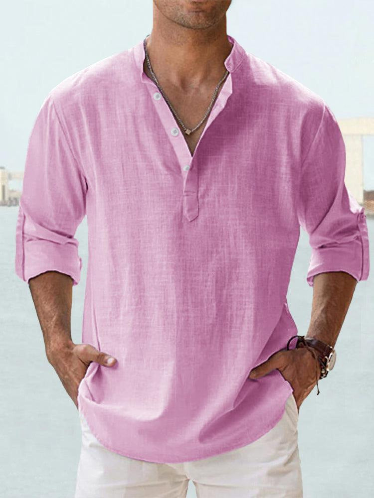 Man wearing a pink shirt with rolled-up sleeves against a light background