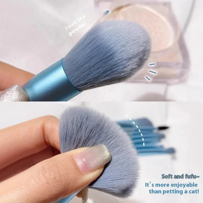 Close-up of a soft, fluffy blue makeup brush for applying powder, held by a hand with manicured nails.