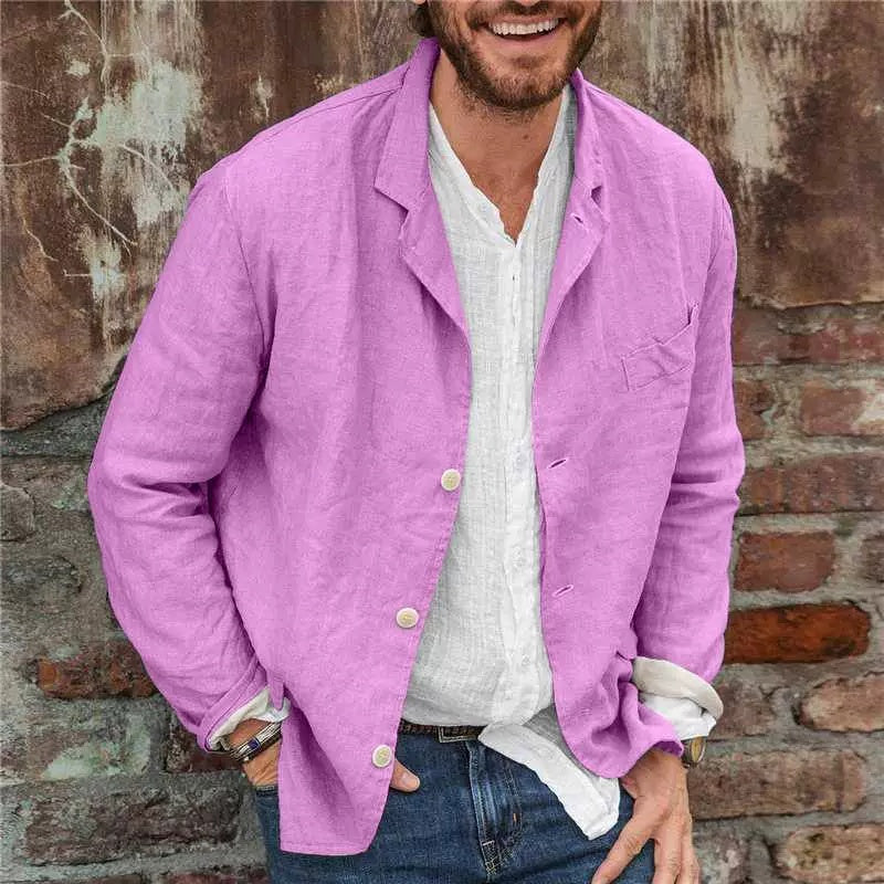 Man wearing a purple jacket over a white shirt against a brick wall.