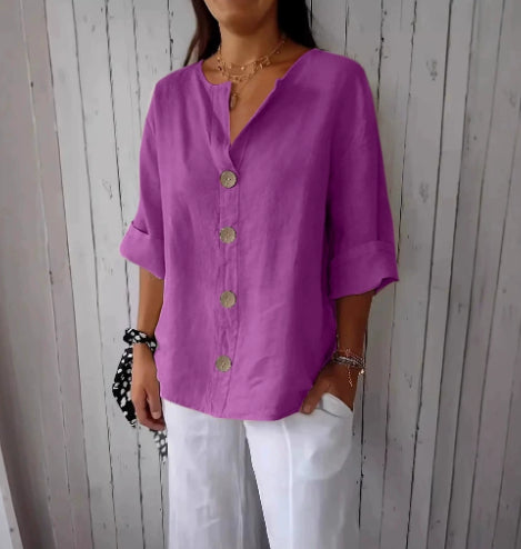 Person wearing a purple button-up shirt and white pants against a wooden panel background