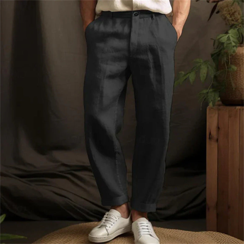 Person wearing dark pants and white sneakers in a casual setting with plants.
