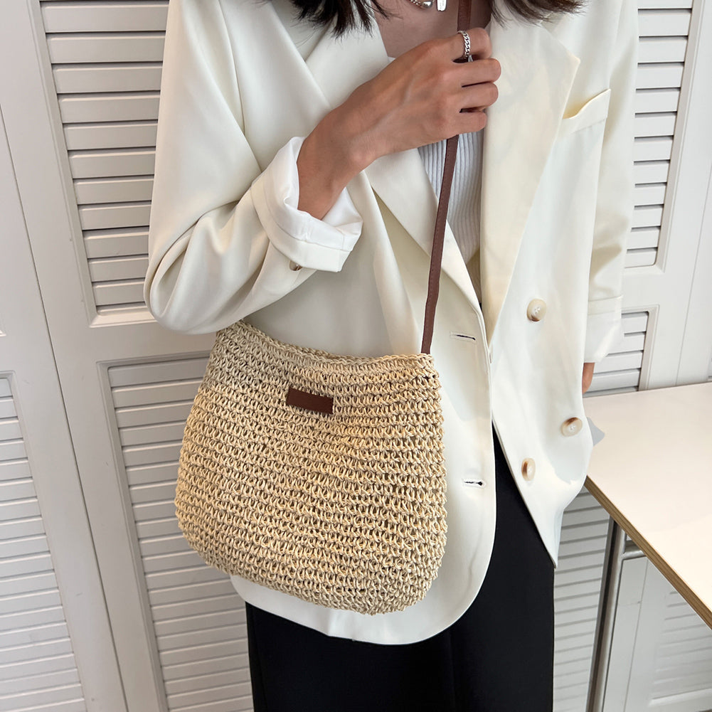 Person wearing a white blazer with a straw handbag against a neutral background