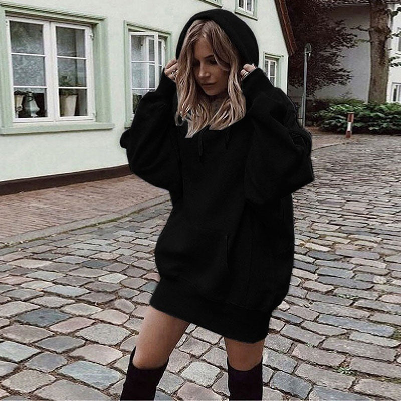 Person wearing a black hoodie on a cobblestone street.