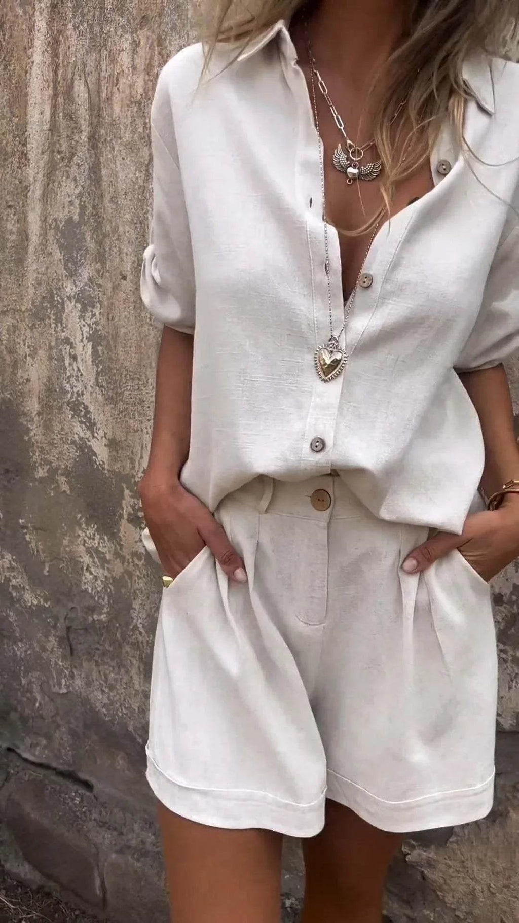 Woman wearing a stylish beige linen shirt and shorts set from ZA-Zola, accessorized with layered necklaces.