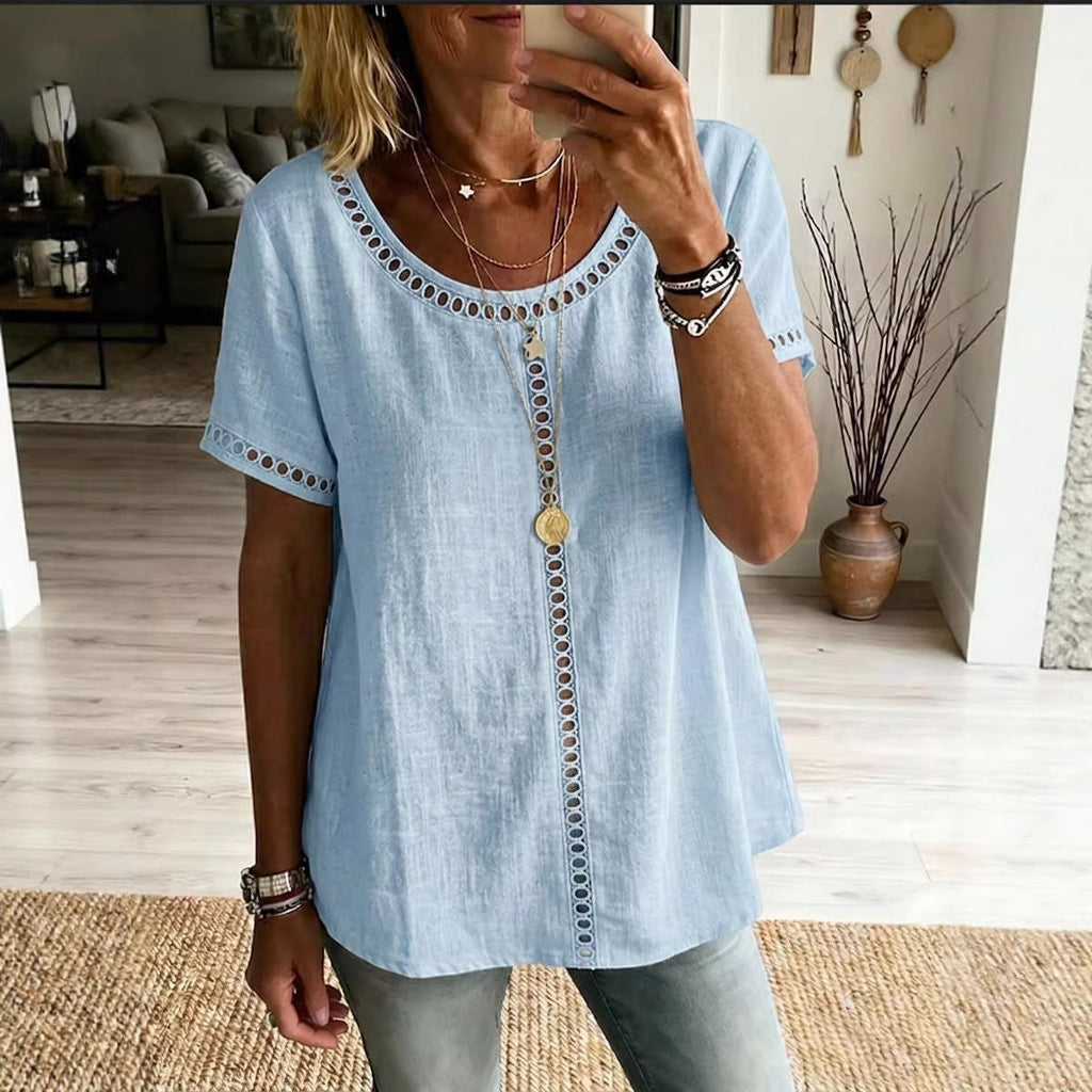 Woman wearing a light blue top with decorative buttons in a living room.