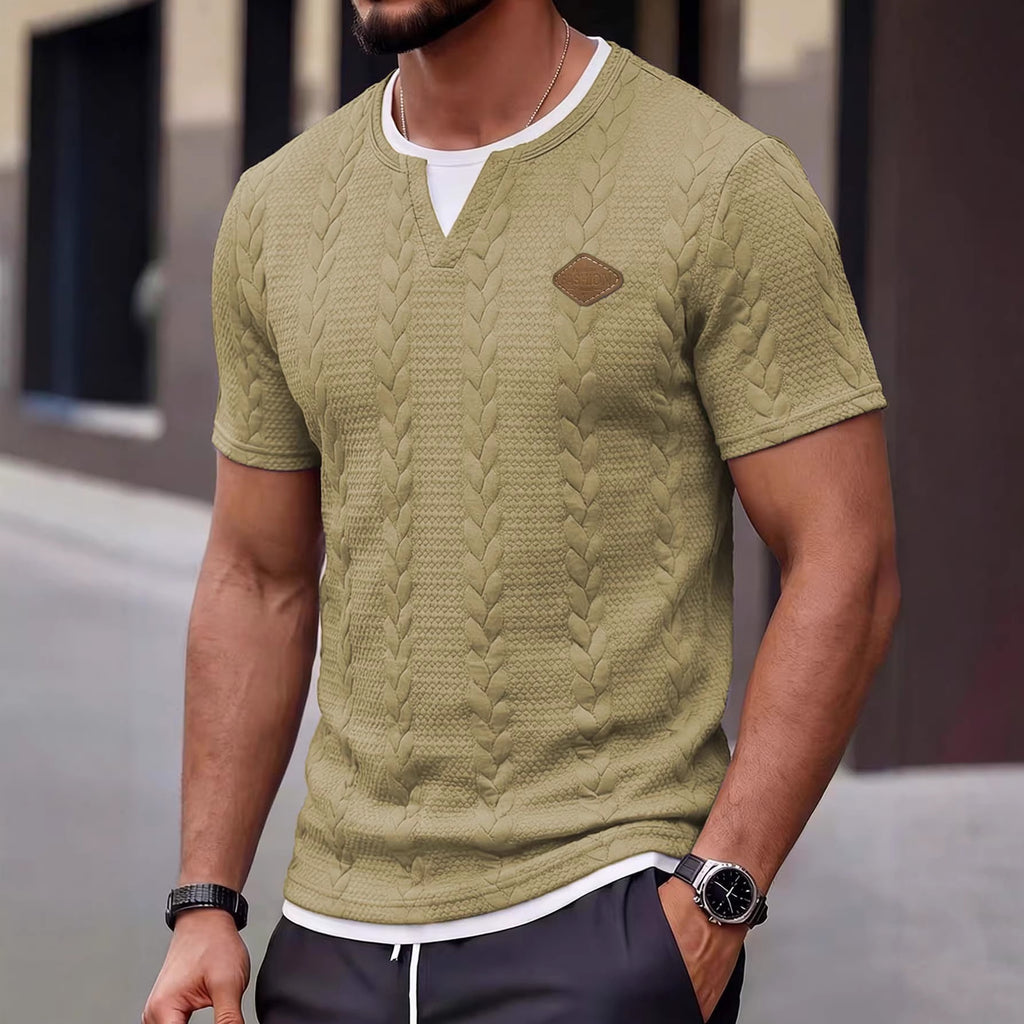 Man wearing a green textured knit shirt with a brand logo, standing outdoors.