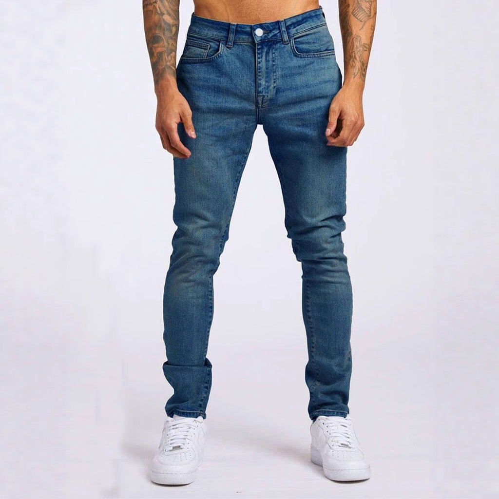 Person wearing blue jeans and white sneakers on a plain background