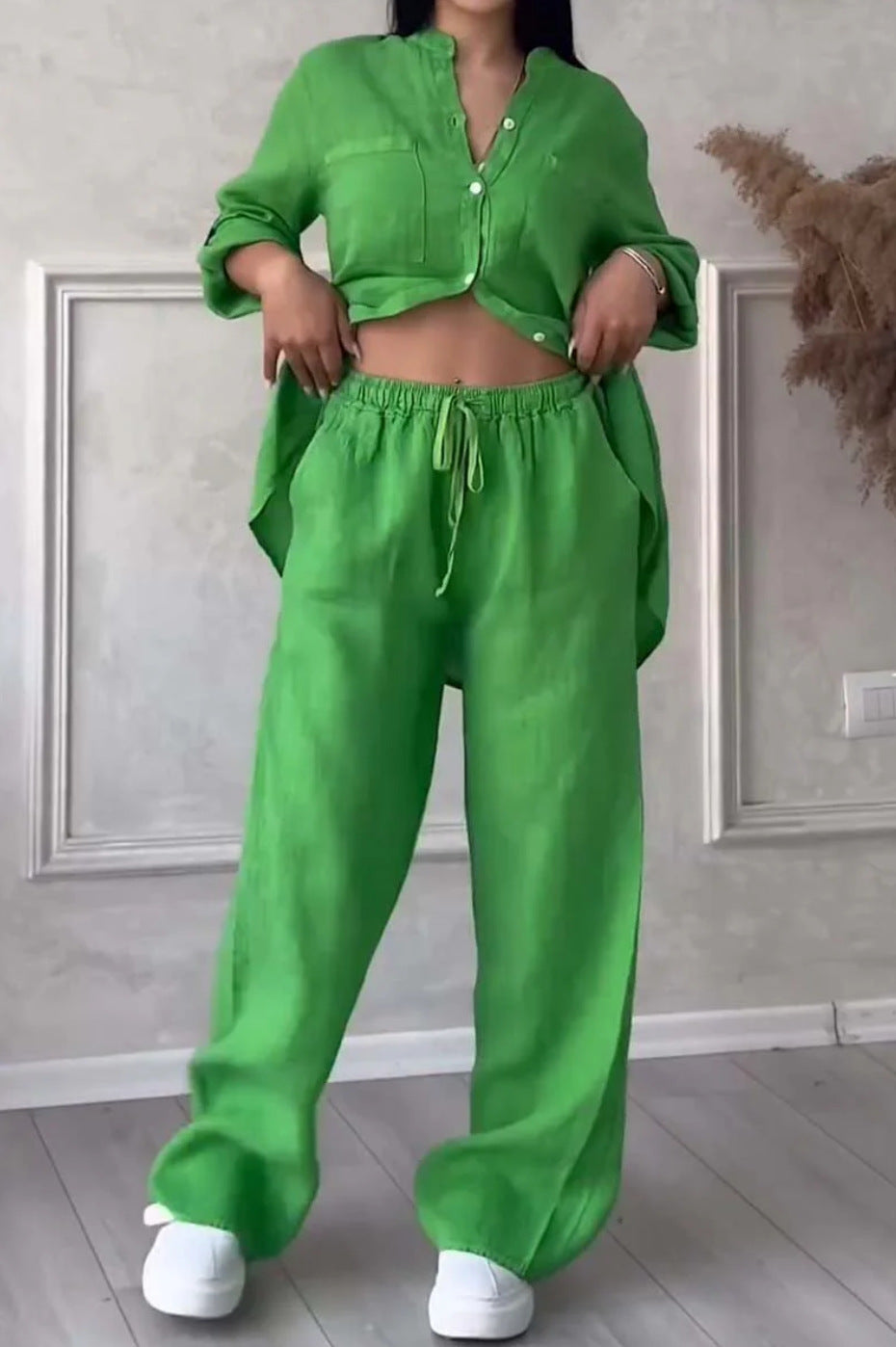 Person wearing a bright green outfit with a matching top and pants in a minimal indoor setting.