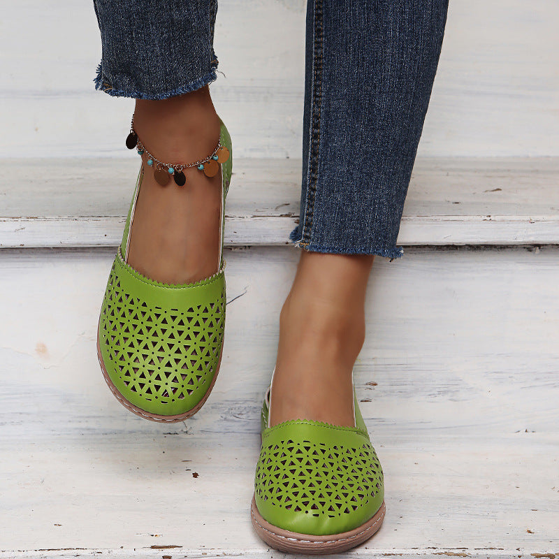 Green perforated shoes worn with blue jeans on a light wooden floor.