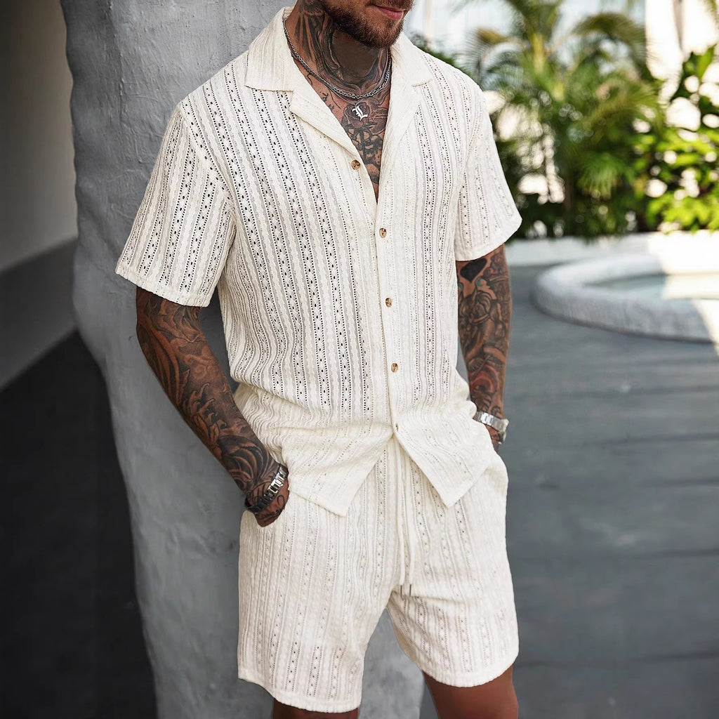 Man wearing a white embroidered outfit with tattoos in an outdoor setting