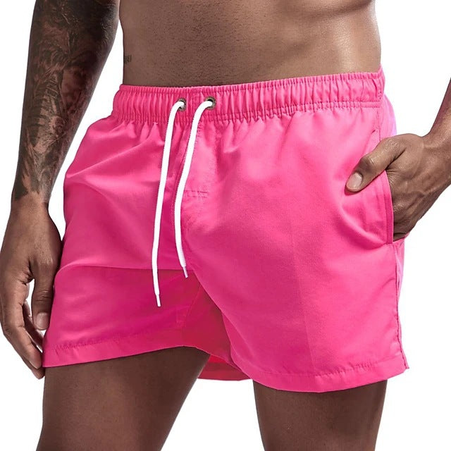 Person wearing bright pink swim shorts with a white drawstring on a plain background