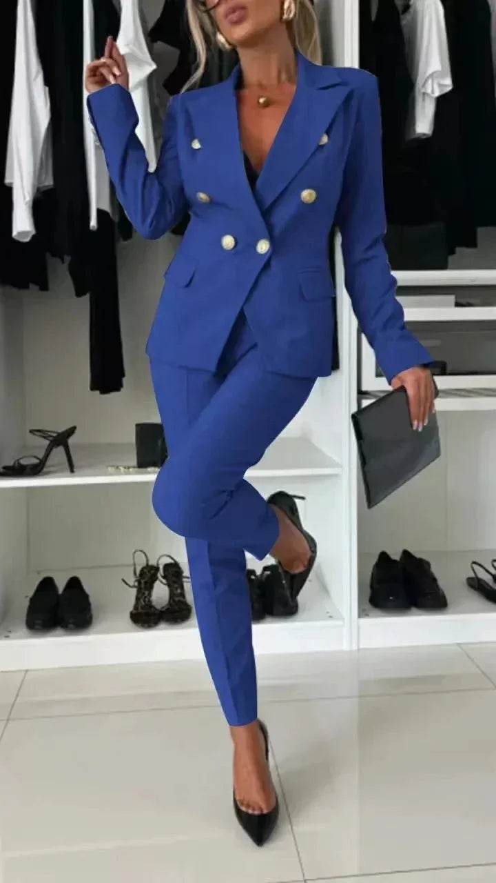 Woman wearing a blue double-breasted suit with gold buttons, black heels, and clutch in modern closet, ZA-Zola fashion.