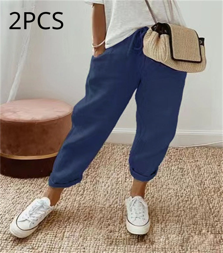 Person wearing blue pants and white sneakers with a beige bag, standing on a carpeted floor.