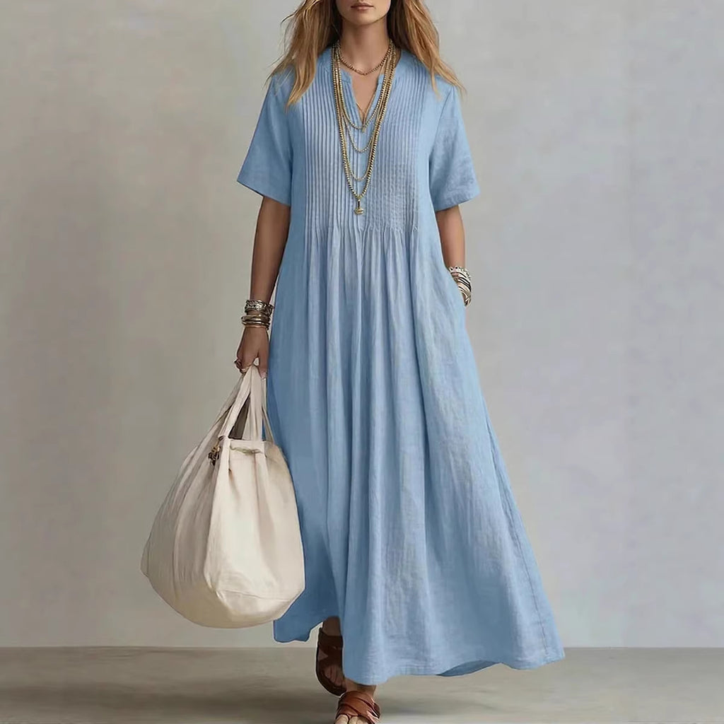 Woman wearing a blue dress holding a white bag against a neutral background