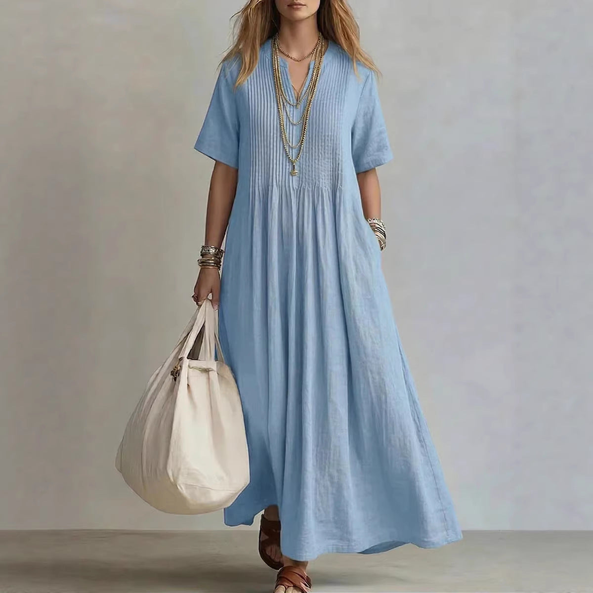 Woman wearing a blue dress holding a white bag against a neutral background