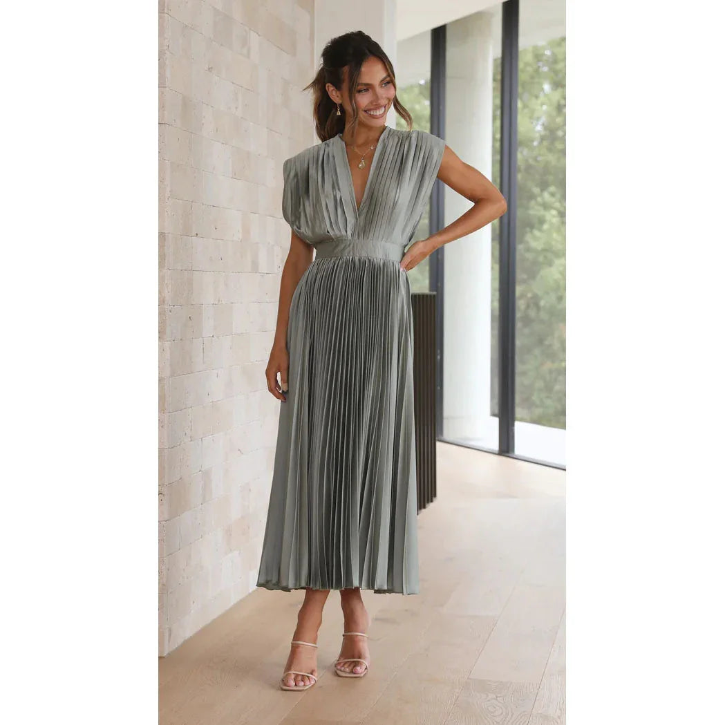 Woman wearing a gray pleated dress standing indoors.