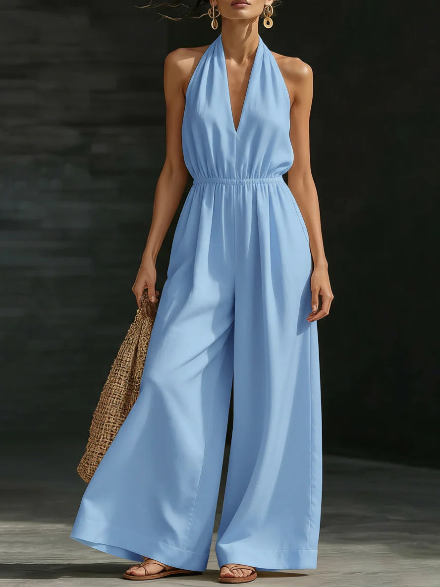 Woman wearing a light blue jumpsuit holding a woven bag against a dark background