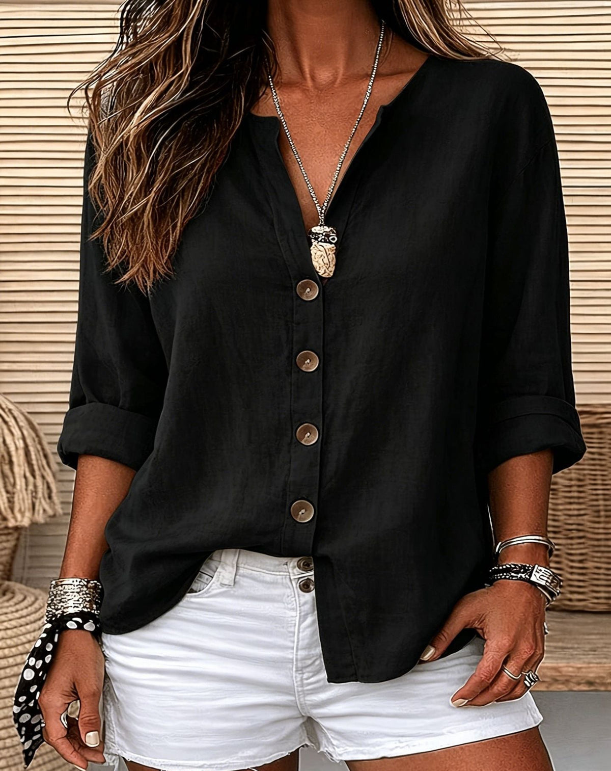 Person wearing a black button-up shirt and white shorts with a neutral background