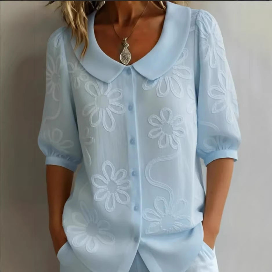 Light blue blouse with floral embroidery on a plain background