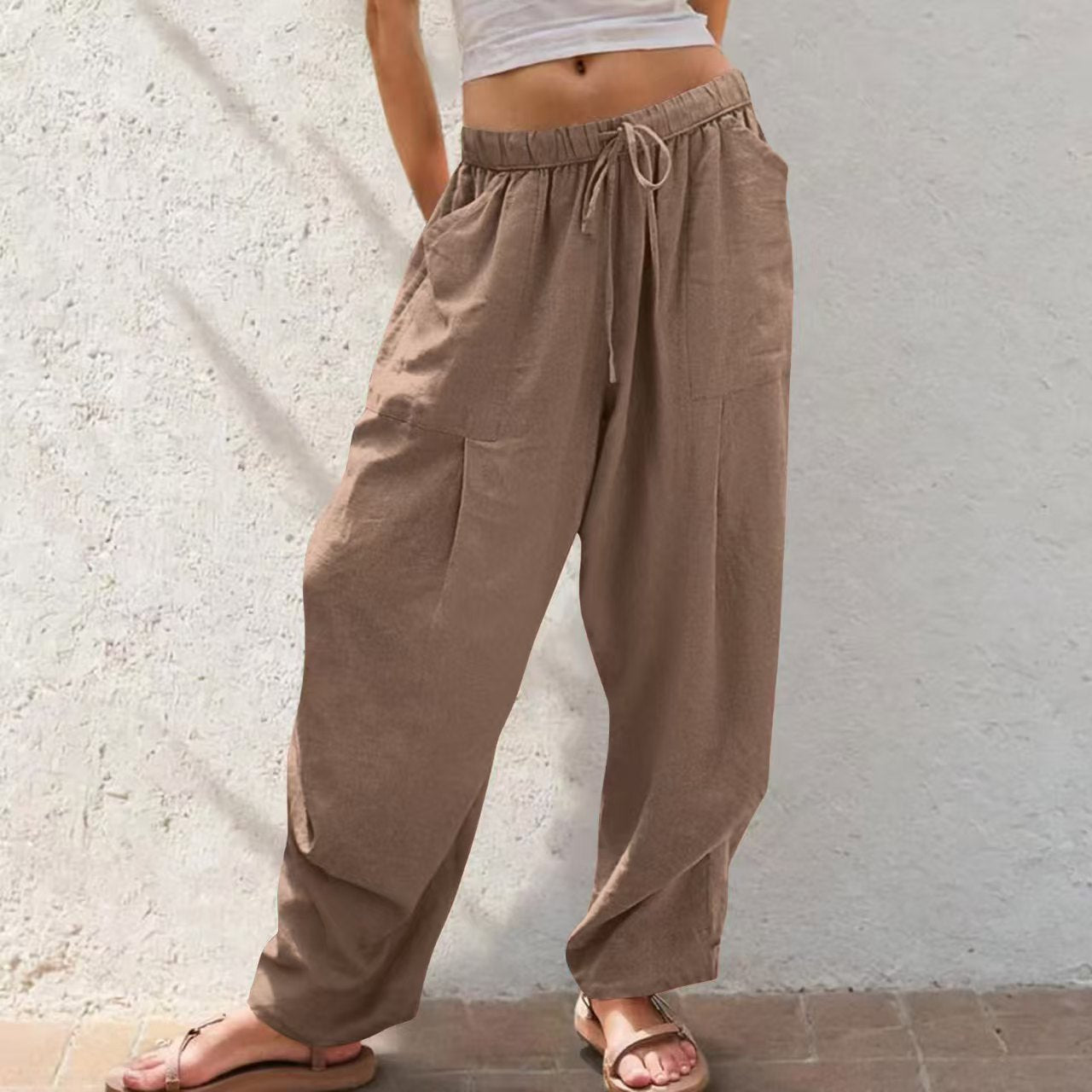 Brown wide-leg pants worn by a person against a light stone wall.