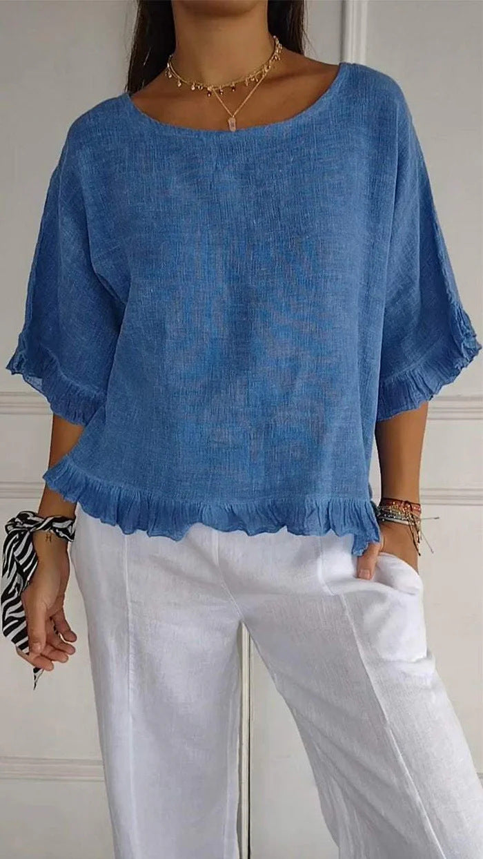 Person wearing a blue top and white pants against a neutral background