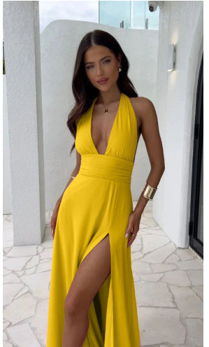 Woman wearing a yellow dress with a high slit, standing outdoors.