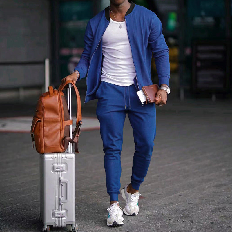 Person in blue tracksuit with suitcase and backpack walking outdoors