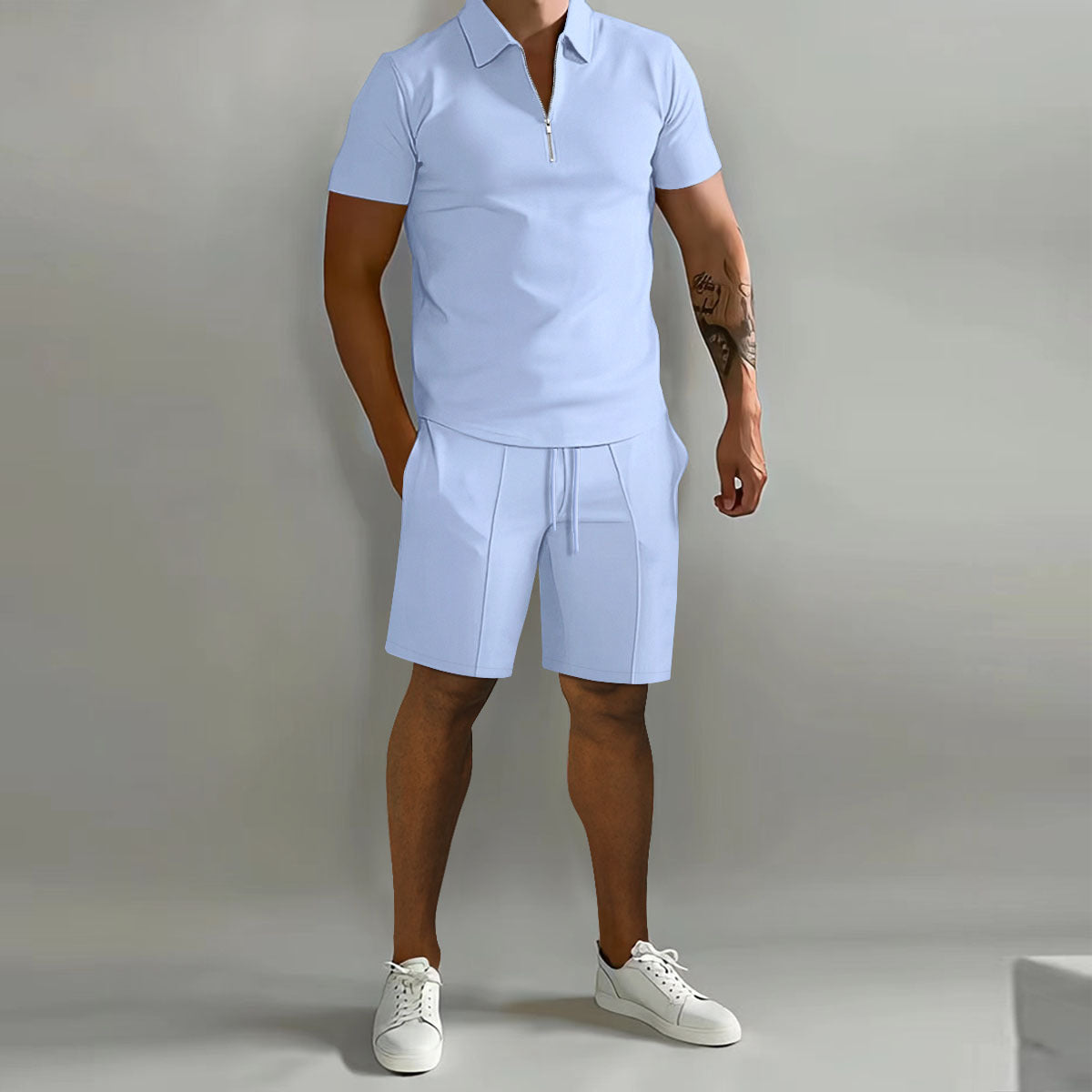 Person wearing a light blue polo shirt and shorts set with white sneakers on a plain background