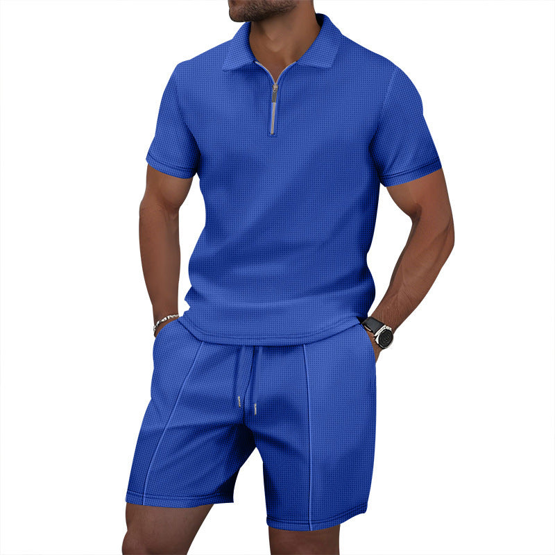 Man wearing a blue textured polo shirt and shorts set on a white background
